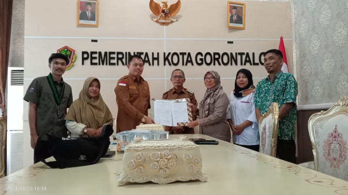 Kepala Badan Kesatuan Bangsa dan Politik Kota Gorontalo, Iskandar S. Moerad (kiri) saat menyerahkan berita acara serah terima hibah dalam bentuk uang kepada Ketua Majelis Daerah (MD) Korps Alumni Himpunan Mahasiswa Islam (KAHMI) Kota Gorontalo, Kristina Mohamad Udoki (kanan).